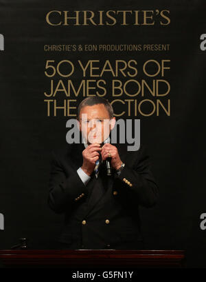 Sir Roger Moore hält eine Maske des aktuellen James-Bond-Schauspielers Daniel Craig bei Christie's 50 Years of James Bond Sale, mit Erinnerungsstücken, die von der Bond-Besetzung gespendet wurden, in Christie's in South Kensington, London. Stockfoto