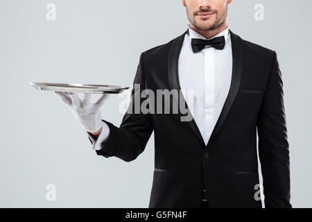 Nahaufnahme des jungen Kellner im Smoking und Handschuhe halten Silbertablett Stockfoto
