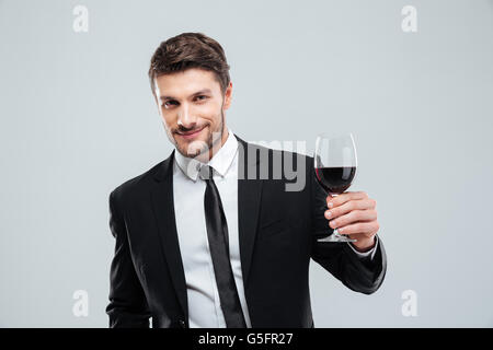 Lächelnde junge Geschäftsmann hält Glas Rotwein über weißem Hintergrund Stockfoto
