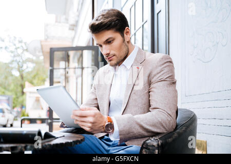 Schöner junger Mann mit TabletPC zu berühren, in einem Café im freien