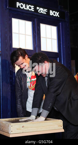 Schauspieler Matt Smith (links), der aktuelle Dr Who, der als Doctor Who Hauptautor Steven Moffat zuschaut, wirft seine Handdrucke in Zement, während seines ersten Besuches bei The Doctor Who Experience in Cardiff Bay, um eine neue Ausstellung von Monstern und Requisiten aus der Serie 7 zu enthüllen. Stockfoto