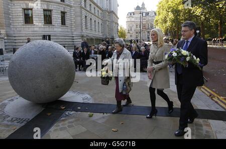 Während einer Zeremonie anlässlich des 10. Jahrestages der Terroranschläge in Bali, Indonesien, am Bombendenkmal in Westminster, London, kommen Menschen an, um Blumen an das Denkmal zu legen. Stockfoto