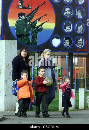 Eine Familie geht an einem IRA-Mural in der republikanischen Enklave Ballymurphy im Westen Belfasts vorbei, als Sinn-Fein-Präsident Gerry Adams Vorschläge ablehnte, die IRA habe sich dem Druck von Ulster-Gewerkschaftern bei der Stilllegung ihrer Waffen gebeugt. Stockfoto