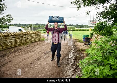 Leute kommen und Park in schlammigen und aufgeweichten Felder beim Glastonbury Festival am Standort würdig Farm, Somerset, wo schwere Regen über einen längeren Zeitraum verursacht hat isoliert Überschwemmungen und schlammige Feldern. Stockfoto