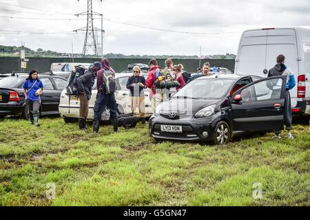 Leute kommen und Park in schlammigen und aufgeweichten Felder beim Glastonbury Festival am Standort würdig Farm, Somerset, wo schwere Regen über einen längeren Zeitraum verursacht hat isoliert Überschwemmungen und schlammige Feldern. Stockfoto