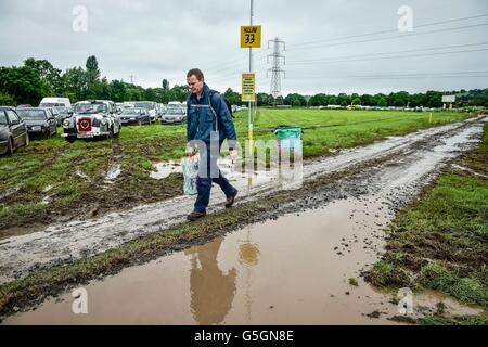 Leute kommen und Park in schlammigen und aufgeweichten Felder beim Glastonbury Festival am Standort würdig Farm, Somerset, wo schwere Regen über einen längeren Zeitraum verursacht hat isoliert Überschwemmungen und schlammige Feldern. Stockfoto