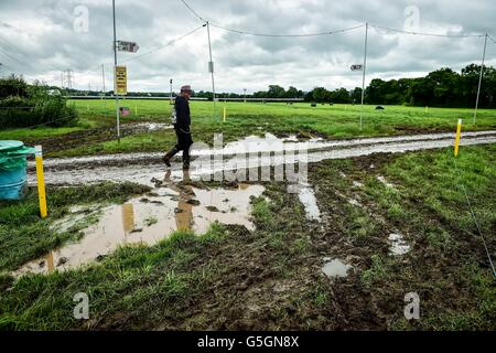 Leute kommen und Park in schlammigen und aufgeweichten Felder beim Glastonbury Festival am Standort würdig Farm, Somerset, wo schwere Regen über einen längeren Zeitraum verursacht hat isoliert Überschwemmungen und schlammige Feldern. Stockfoto