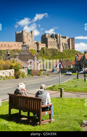 Großbritannien, England Northumberland, Bamburgh, paar auf Bank, die Burg zu bewundern, von dem Dorfplatz Stockfoto