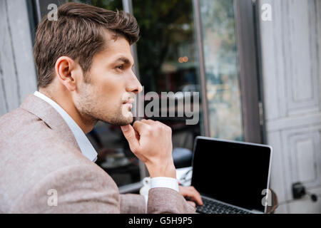 Nahaufnahme von Ernst hübscher Geschäftsmann mit modernen Laptop in Coffee-shop Stockfoto