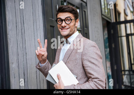 Jungen Nerd Mann in Brillen Grimasse und Anzeichen von v Stockfoto