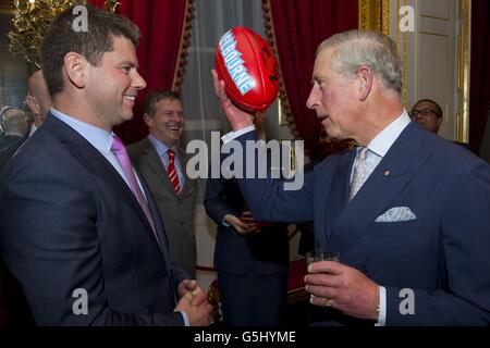 Prinz Charles hält einen australischen Fußball, nachdem er ihn vom ehemaligen australischen Fußballspieler Tony Woods (links) im St. James's Palace im Zentrum von London während eines Empfangs für prominente Papua-Neuguineer, Australier und Neuseeländer, die vor ihrer Tour in Papua-Neuguinea im Vereinigten Königreich leben, erhalten hat. Australien und Neuseeland. Stockfoto