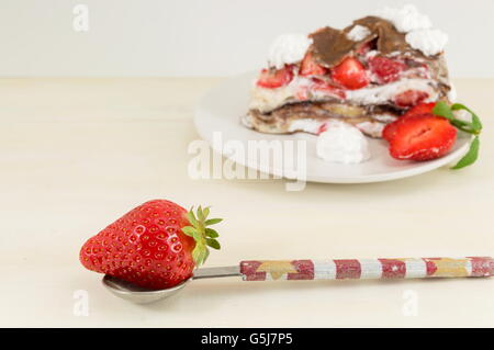 Erdbeeren in einem Löffel mit Stück Erdbeerkuchen Stockfoto