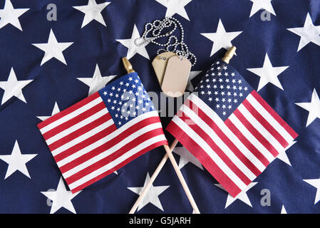 Draufsicht auf zwei gekreuzten amerikanische Flaggen auf dem Stern eine große Fahne mit militärischen Erkennungsmarken. Perfekt für Veterans Day, Memor Stockfoto