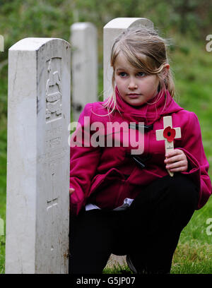 Ein unbenannter Grundschüler aus York legt ein Mohnkreuz auf einem Kriegsgrab auf dem York Cemetery, während der York Cemetery Trust und die Fulford British Legion zwei Tage lang verschiedene Schulen im Raum York besuchten, um über den Remembrance Day und die Geschichte dahinter zu berichten. Stockfoto