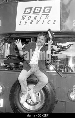 Dave Lee Travis, Moderator der BBC World Service-Show „A Jolly Good Show“, zieht seinen Hut vor dem umgebauten Doppeldeckerbus der Nachrichtenorganisation im Bush House in London. Der Bus, ausgestattet als mobiles Ausstellungszentrum, wird durch Europa reisen, um den World Service zu fördern. Stockfoto
