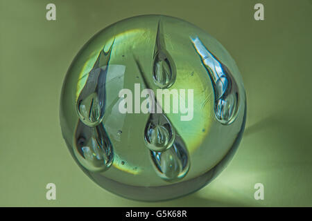 Transparente Glaskugel mit Silber Bläschen auf grünem Hintergrund Stockfoto
