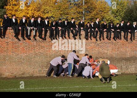 Schüler aus Eton sitzen als Umpire an der Wand, Doktor Michael Atkinson überwacht die Schläger, als die Oppidans 0-0 zusammen mit den Collegers beim jährlichen St. Andrew's Day Eton Wall Game am Eton College, Bukshire, zogen. Der Sohn des Prinzen von Wales, Prinz Harry, nahm an dem diesjährigen Spiel Teil. Stockfoto