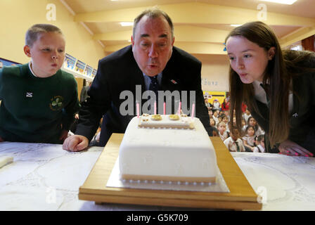 Schottlands erster Minister Alex Salmond mit Schülern l-r Ben Dougall und Chloe Rutkiewicz, als sie Kerzen auf einem Geburtstagskuchen an der St. Patrick's Primary School in Glasgow ausblasen, nachdem er sie besucht hatte, um ihnen zu helfen, den 50. Geburtstag der Schule zu feiern, an dem Tag, an dem der erste Minister Schottlands längste wurde Als erster Minister, nachdem er 2002 volle Tage im Amt erreicht hat. Stockfoto