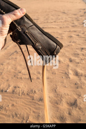 Hand gießen Sand aus dem Schuh in Wüste Stockfoto