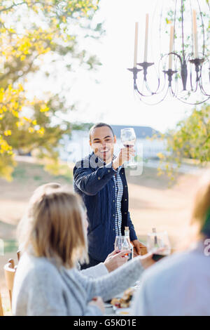 Freunde, toasten mit Wein am Gartentisch Stockfoto