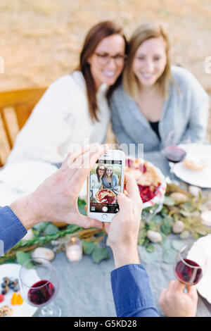 Kaukasischen Mann Fotografieren Freunde am Gartentisch Stockfoto