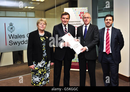 Paul Silk (zweiter rechts) übergibt David Jones MP, Staatssekretär für Wales (zweiter links), Teil 1 des Berichts der Seidenkommission, der von Baroness Jenny Randerson, Ministerin des Büros von Wales (links) und Stephen Crabb, MP, Minister des Büros von Wales (rechts), im Büro von Wales, Cardiff beobachtet wurde. Stockfoto