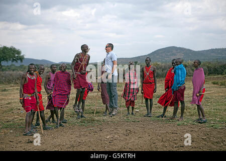 Gruppe der Massai-Krieger und ein Tourist einen zeremoniellen Tanz in ein Massai-Dorf, Kenia, Afrika zu tun. Stockfoto