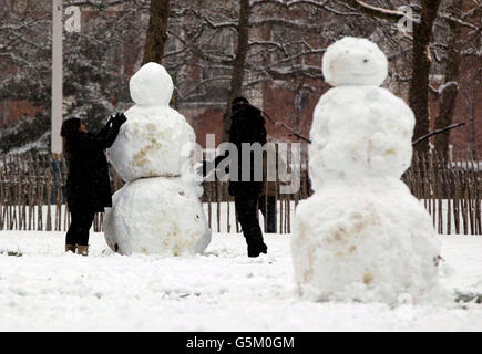 Menschen, die einen Schneemann im St James Park im Zentrum von London bauen. Stockfoto