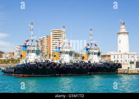 Leuchtturm und drei Schlepper Boot Schiffe vor Anker im Hafen von Malaga, Andalusien, Spanien. Stockfoto