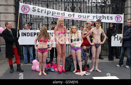 Aisling Fitzgibbon (vorne, 3. Links) alias 'The Girl Against Fluoride' mit Unterstützern, die sich vor dem Leinster House ausziehen, um die Kosten für die Zugabe von Chemikalien einschließlich Fluorid zur Wasserversorgung hervorzuheben, während Gewerkschaftsmitglieder gegen Sparmaßnahmen durch das Stadtzentrum von Dublin marschieren. Stockfoto