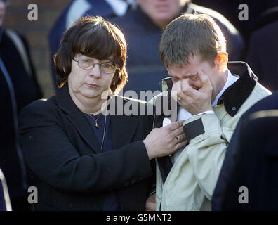 Marie McColgan tröstet ihren Sohn Eamon bei der Beerdigung ihres anderen Sohnes Daniel McColgan auf dem Rathcoole-Anwesen im Norden von Belfast. McColgan wurde am frühen Morgen des 12/1/02 in einer Sortierstelle im loyalen Rathcoole-Anwesen zur Arbeit angeschossen. * der Mord wurde von den Red Hand Defenders behauptet, die damit drohten, dass auch andere katholische Postmitarbeiter legitime Ziele sein würden. Alle Postarbeiter in Nordirland veranstalteten eine 24-stündige Unterbrechung als Zeichen des Respekts für ihren ermordeten Kollegen, und eine große Anzahl von Personen, die mit ihm in Belfast arbeiteten, nahmen an der Beerdigung Teil. Stockfoto