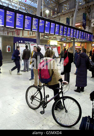 Eine Frau, die mit ihrem Fahrrad unterwegs ist und am Londoner Bahnhof Waterloo nach Zuginformationen sucht, zu Beginn des letzten 48-stündigen Eisenbahnstreits zwischen der Gewerkschaft Rail Maritime and Transport (RMT) und South West Trains (SWT). Stockfoto