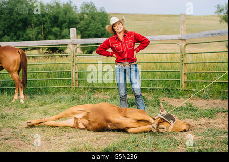 Kaukasische Cowgirl lächelnd mit gebundenen Rinder auf ranch Stockfoto