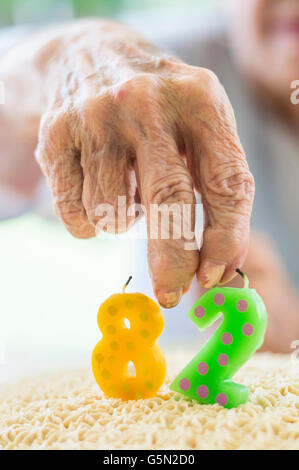 Nahaufnahme von faltige Hand hält Geburtstag Kuchen Kerze Stockfoto