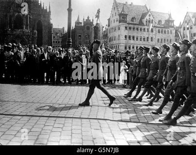 1923: Stosstruppen marschieren am 'Großen Deutschen Tag' in Nürnberg, Bayern, vorbei an ihrem Führer, Adolf Hitler (2. Links, Trenchcoat), Politikern und bayerischen Mitgliedern der ehemaligen deutschen Reichsarmee. Schätzungsweise 100,000 Personen haben an der Veranstaltung teilgenommen. Stockfoto