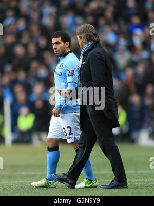 Manchester-City-Manager Roberto Mancini (rechts) chattet mit Carlos Tevez, bevor der Spieler auf das Spielfeld wechselt Stockfoto