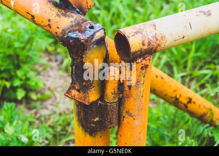 alte rostige gelbe Rohr auf einem Hintergrund von grünem Rasen Stockfoto