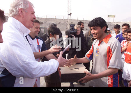 Die Botschafter des Fußballverbands Lawrie McMenemy (links) und der ehemalige Spieler von Tottenham Hotspors, Gary Mabbutt (zweiter links), geben den Spielern des FC Kabul im Olympiastadion in Kabul, Afghanistan, neue Fußballschuhe aus. * McMenemy und Mabbutt sind in dem vom Krieg zerrissenen Land, um die Seite und ein Armeeteam aus Soldaten der ISAF (International Security Assistance Force) aus Großbritannien, Italien, Deutschland und Holland für ein Spiel morgen zu trainieren. Das Olympiastadion ist berüchtigter für die Hinrichtungen, die dort vom ehemaligen Taliban-Regime abgehalten wurden, als für seine Sportereignisse. Stockfoto