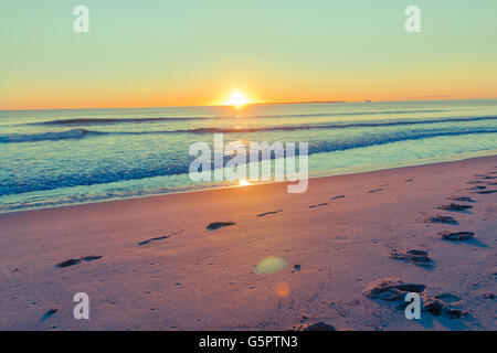 Rückwirkung Küsten breiten Bild Objektiv flare führende, Spuren im Sand aus dem Meer und Horizont bei Sonnenaufgang Stockfoto