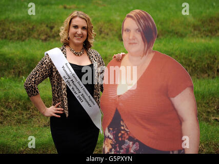 Rosemary Conley Diet and Fitness Magazine Yummy Mummy Slimmer of the Year 2013 Laura Mack aus Tamworth posiert mit einem Foto von sich selbst, bevor sie während eines Fotoanrufs in der Marriott County Hall, London, Gewicht verliert. Stockfoto