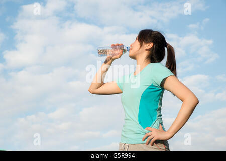 Sport Woman - junge Asiatin Trinkwasser während Joggen. Asiatische Frau Trinkwasser aus der Flasche. Stockfoto