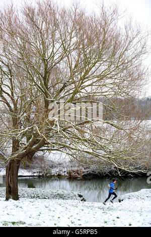 Eine Person rennt entlang der River Cam bei Grantchester Meadows in Cambridgeshire, als heute Teile Englands mit Schnee von bis zu 10 cm in einigen Gegenden getroffen wurden, was Befürchtungen vor Reisechaos auslöste. Stockfoto