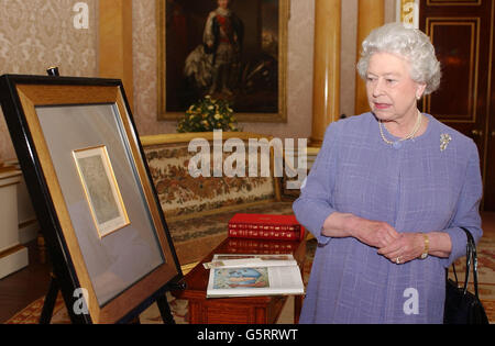 Die britische Königin Elizabeth II. Wirft einen Blick auf das Geschenk eines Gemäldes, das ihr der polnische Präsident Aleksander Kwasniewski geschenkt hat, den sie im Buckingham Palace, London, erhielt. Das Gemälde ist von dem Künstler, Bildhauer, Dramatiker und Schriftsteller, Tymon Nielsiolowski. Stockfoto