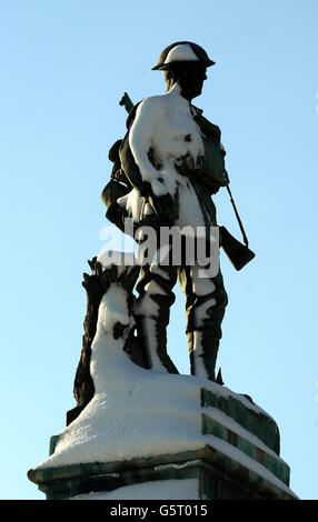 Ein Soldat steht mit Schnee bedeckt auf dem Kriegsdenkmal in Pudsey bei Leeds an dem Tag, an dem weitere Entlassungen in den Streitkräften angekündigt werden. Stockfoto