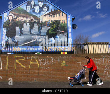 Eine Frau schiebt ein Kind an einem neuen IRA Mural im Westen von Belfast vorbei, die republikanische Bewegung hat gesagt, sie habe einen zweiten Akt der Stilllegung durchgeführt. Stockfoto