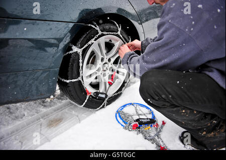 Ein Mann (NACH MODELL GESTELLT) passt THULE CG-9 Snow-Chains zu einem BMW Hinterradantrieb Fahrzeug zu helfen, durch Schnee fahren, vor allem auf Hinterradantrieb Fahrzeuge, die viel anfälliger für immer stecken aufgrund von Verlust der Traktion sind. Stockfoto