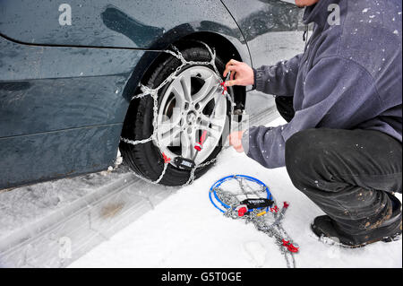 Ein Mann (NACH MODELL GESTELLT) passt THULE CG-9 Snow-Chains zu einem BMW Hinterradantrieb Fahrzeug zu helfen, durch Schnee fahren, vor allem auf Hinterradantrieb Fahrzeuge, die viel anfälliger für immer stecken aufgrund von Verlust der Traktion sind. Stockfoto