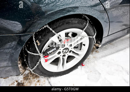 THULE CG-9 Schneeketten, am Hinterrad, aber noch nicht am Gurtstraffer angeschlossen, an ein BMW-Fahrzeug mit Hinterradantrieb. Die Snow-Chains helfen beim Durchfahren von Schnee, insbesondere bei Fahrzeugen mit Hinterradantrieb, die viel anfälliger sind, aufgrund von Traktionsverlusten festzustecken. Stockfoto