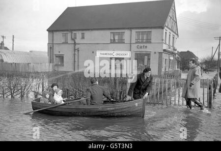 Eine Frau und zwei Kinder fahren mit dem Boot entlang des Thameside Crescent auf Canvey Island in Essex. Stockfoto