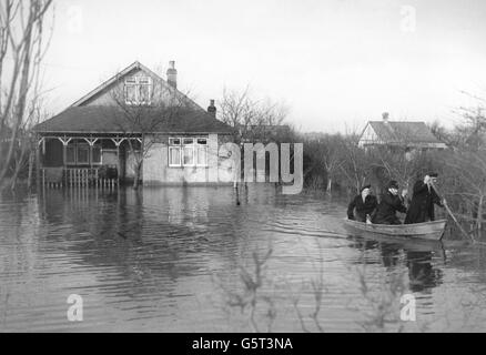 Ein Polizist und Rettungsarbeiter rudern ein Flutopfer aus ihrem Haus auf Canvey Island, Essex. Stockfoto